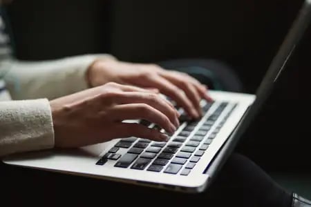Close-up of hands typing on a laptop