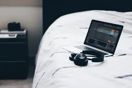 Laptop and headphones sitting on a bed